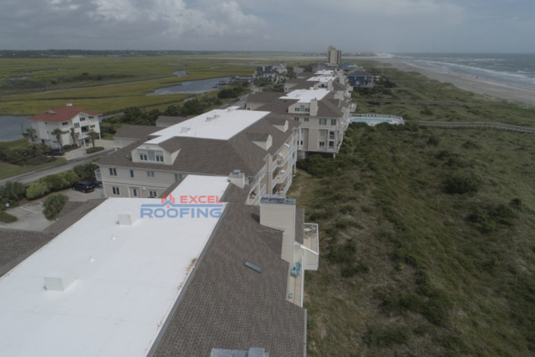 Aerial view of luxury condos in Wrightsville Beach, NC, with new shingle and TPO roofs installed by Excel Roofing Company.